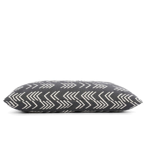 Close-up of The Foggy Dog's DOG BED (S, MODERN MUD CLOTH BLACK) with a dark gray background and white geometric arrow patterns. The fabric texture is visible, and the pillow is positioned at an angle, showcasing the stitching. Made in the USA with an eco-friendly insert, this boho minimalist dog bed adds style to any space.