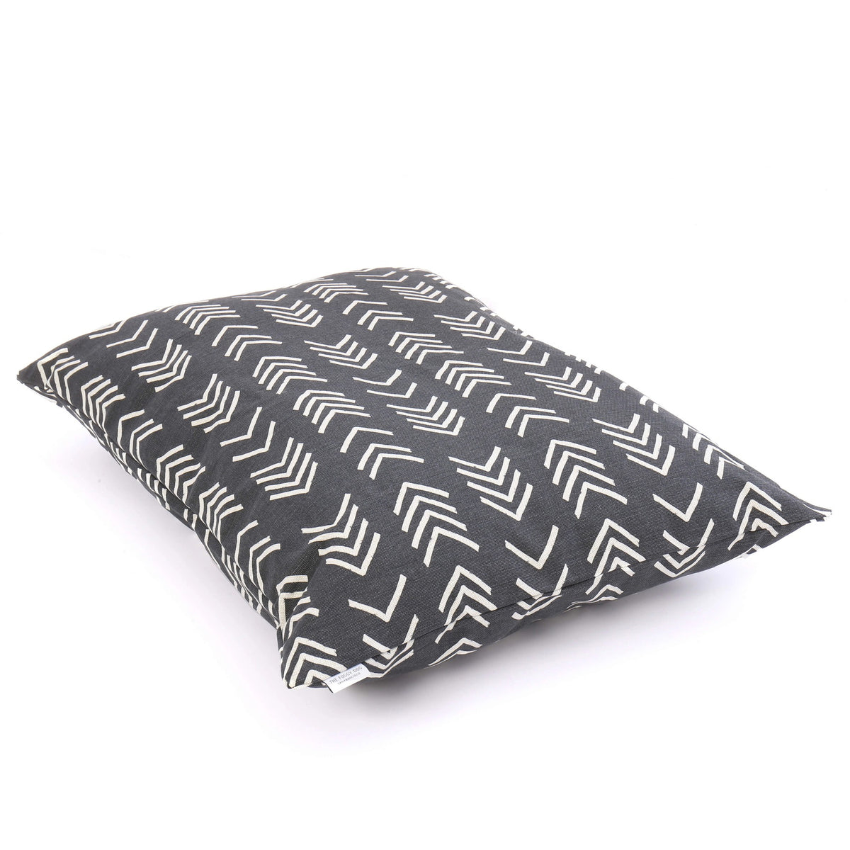 Close-up of The Foggy Dog&#39;s DOG BED (S, MODERN MUD CLOTH BLACK) with a dark gray background and white geometric arrow patterns. The fabric texture is visible, and the pillow is positioned at an angle, showcasing the stitching. Made in the USA with an eco-friendly insert, this boho minimalist dog bed adds style to any space.