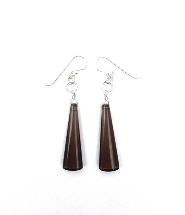 These ANN LIGHTFOOT Smokey Quartz Long Drop Earrings feature sterling silver hook earwires with small connecting rings, from which elegant dark brown teardrop-shaped pendants hang. The pendants, which are slightly wider at the bottom than at the top, have a smooth and glossy finish that adds sophistication to any outfit.