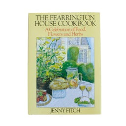 The cover of "Fearrington Signature Collection - The Fearrington House Cookbook by Jenny Fitch" from Belted Goat features an illustrated outdoor garden scene in yellow, with a table set with wine glasses, bread, a pumpkin, and flowers. The subtitle reads "A Celebration of Food Flowers and Herbs.