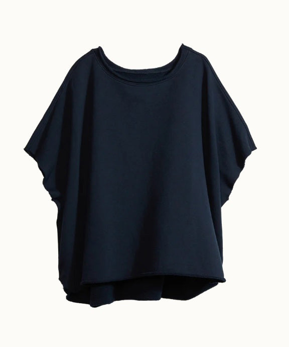 The FRANK &amp; EILEEN OLIVE ORIGINAL CAPELET in black, by FRANK &amp; EILEEN, is a black oversized T-shirt with a round neckline and short, wide sleeves. Made from 100% cotton, it features a loose fit and simple design reminiscent of a capelet against a light textured background.