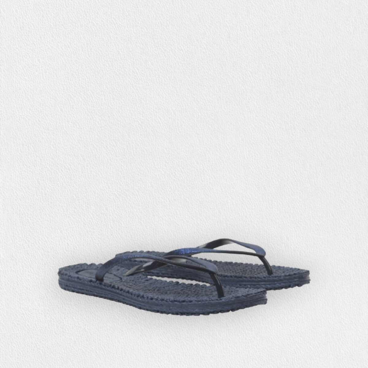 The ILSE JACOBSEN - CHEERFUL FLIP FLOPS IN NAVY from LINES OF DENMARK, characterized by their textured sole and thin straps adorned with glitter stones for added sparkle, are showcased against a plain white background. The cheerful flip-flops are arranged with one slightly overlapping the other to highlight both their style and comfort.