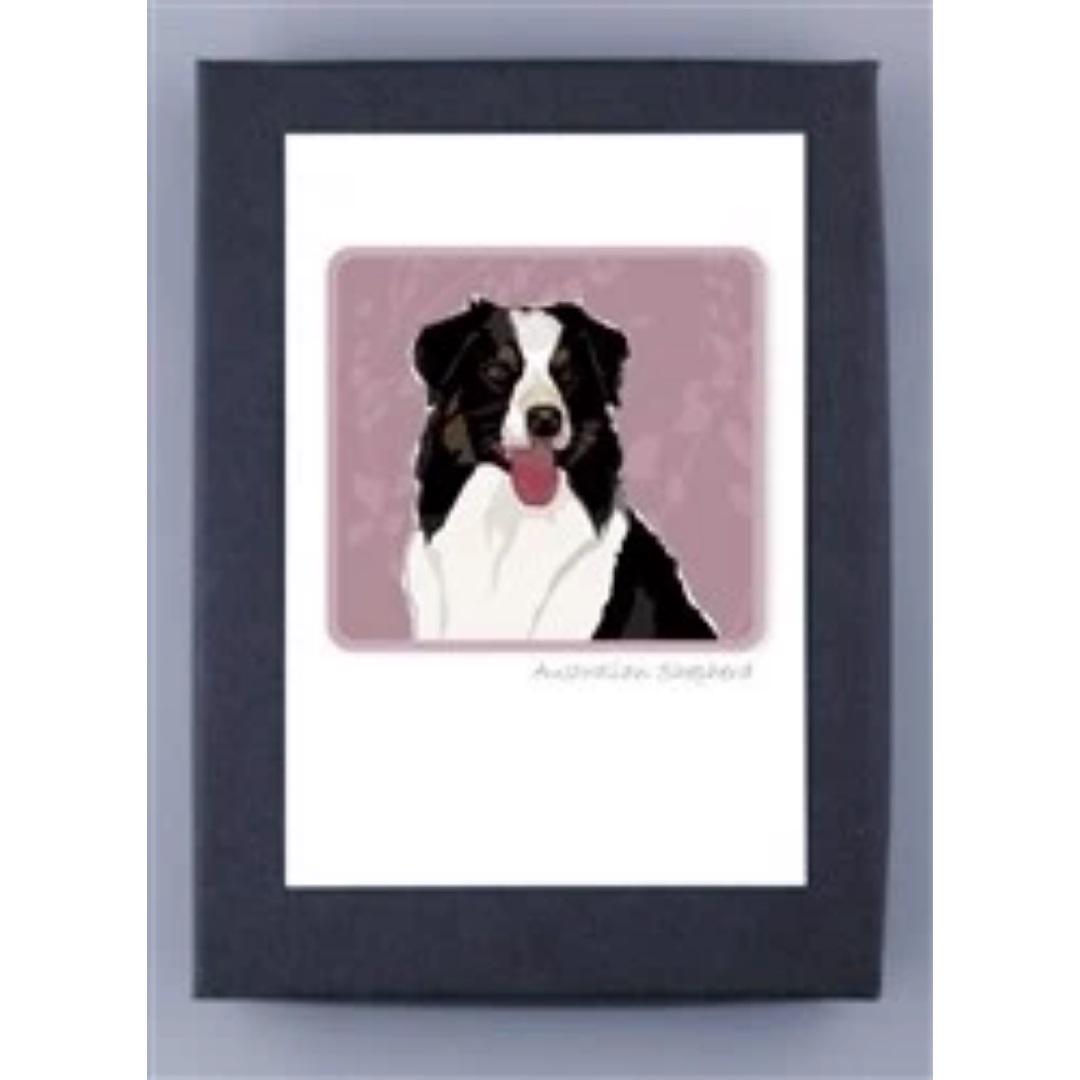 A framed illustration from the PAPER RUSSELS - AUSTRALIAN SHEPHERD NOTE CARDS by PAPER RUSSELLS depicts an Australian Shepherd with a black and white coat. The dog is set against a muted pink background with subtle patterns, its tongue playfully sticking out. Below the illustration, printed on FSC certified recycled paper, the text reads &quot;Australian Shepherd.