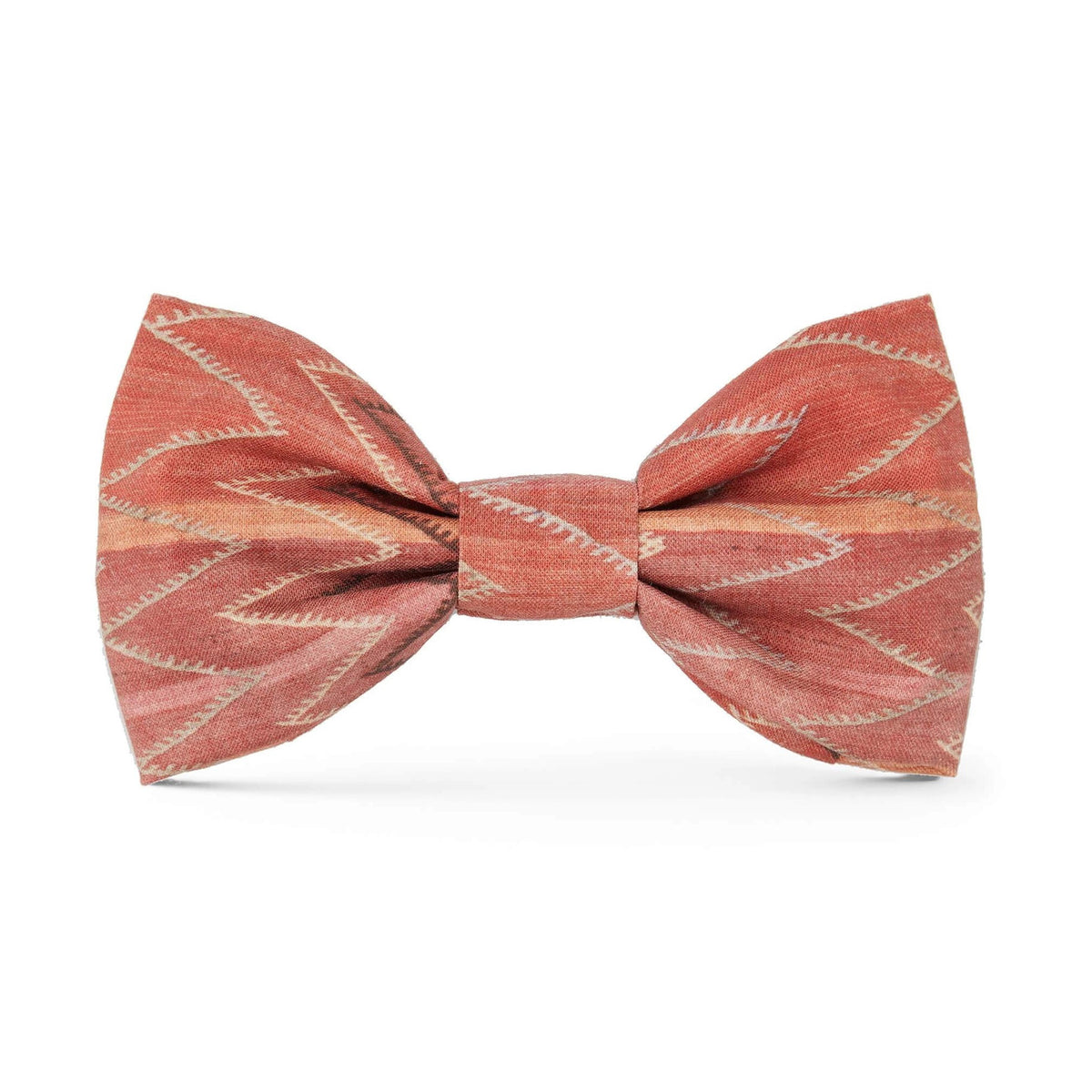 The DOG BOW TIE (STANDARD, ST. FRANK CHEVERON KILIM) by THE FOGGY DOG is a stylish accessory made from rust-colored, textured fabric featuring a white zigzag pattern. This American-made dog bow tie is neatly tied to showcase its elegant design and composition against a solid white background, emphasizing the detailed patterns and rich color.