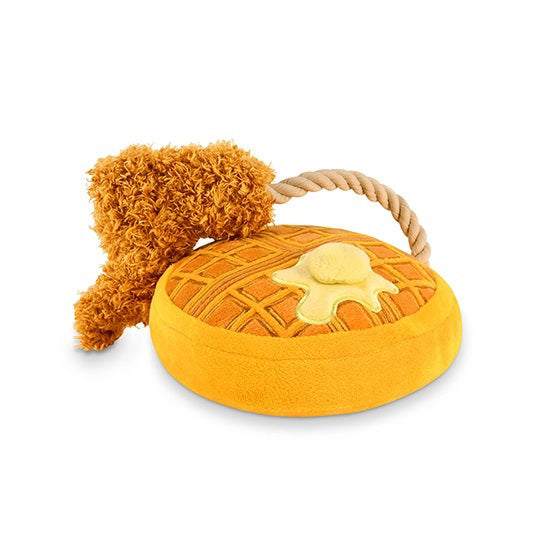 The CHICKEN &amp; WOOFLES by PLAY PET LIFESTYLE is a durable plush toy that looks like a brunch dish, featuring a fluffy brown drumstick attached to a soft, round waffle topped with a yellow dollop mimicking butter. The drumstick is connected to the waffle by a short, twisted rope handle, making it perfect for dog toys.