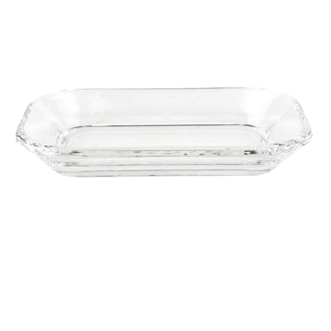 The HOMART CLEAR GLASS SOAP DISH is a transparent, rectangular tray with slightly raised edges. It features a simple, elegant design with a smooth surface, making it ideal for serving food or holding small items. This decorative statement piece ensures full visibility of its contents and is perfect for any formal table setting.