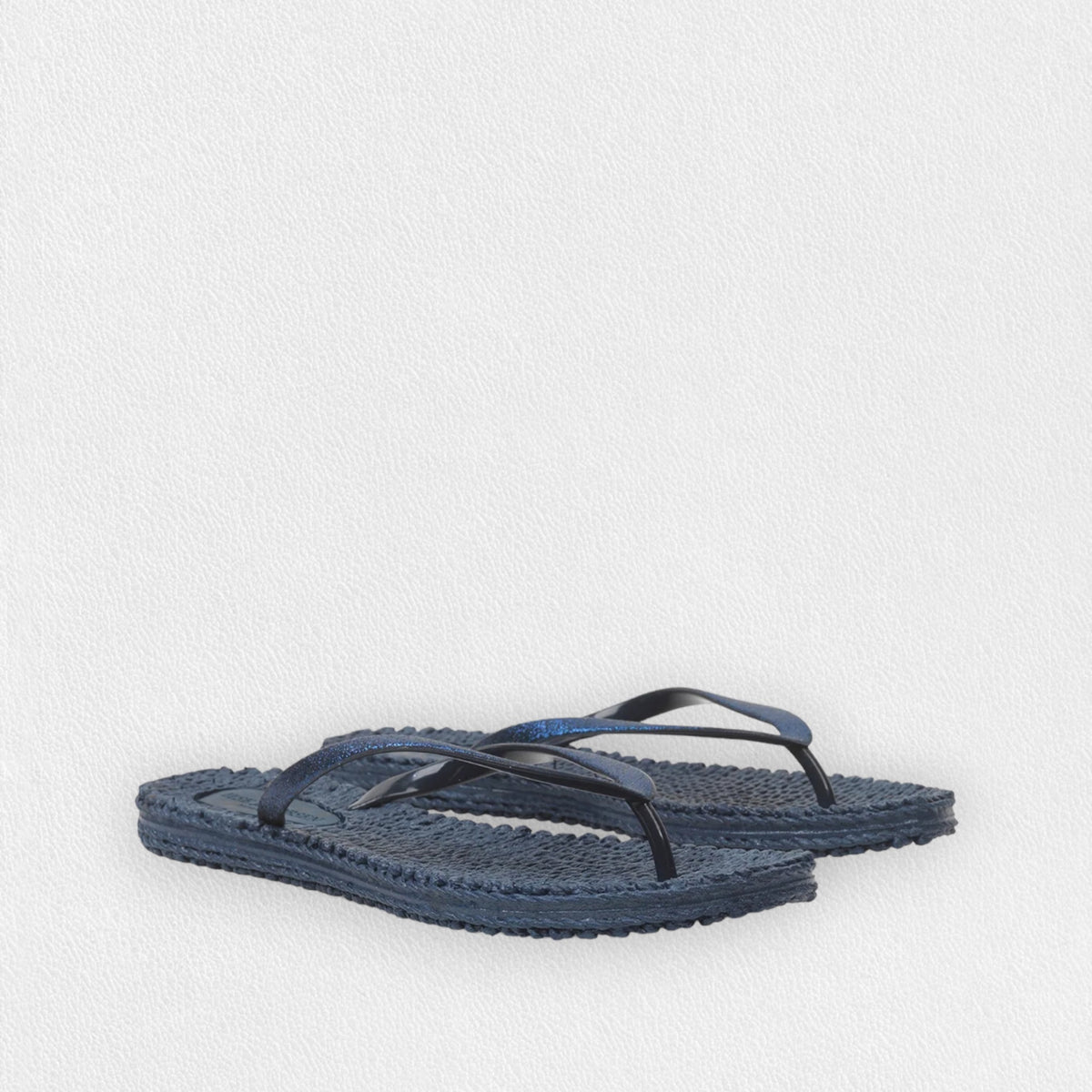 A pair of ILSE JACOBSON - CHEERFUL FLIP FLOPS IN INDIGO by LINES OF DENMARK is placed against a plain white background. These comfortable flip flops have a woven appearance, adding a unique and stylish texture, perfect for a day at the beach.