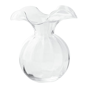 The VIETRI - HIBISCUS MEDIUM VASE CLEAR features a round base and a wide, wavy-edged rim. Inspired by Tuscan artisans, this clear glass vase from VIETRI boasts a smooth, glossy finish and an elegant, flowing design that embodies the beauty of craftsmanship.