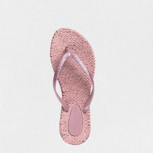 A pair of comfortable ILSE JACOBSEN - CHEERFUL FLIP FLOPS IN MISTY ROSE by LINES OF DENMARK, featuring braided straps adorned with glitter stones and textured soles. The background is a plain white surface. The flip-flops are angled slightly to the left, with the front pair overlapping the toe area of the back pair.