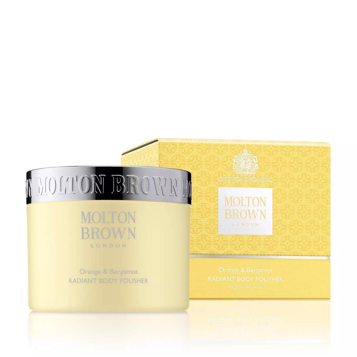 A MOLTON BROWN - ORANGE AND BERGAMOT RADIANT BODY POLISHER jar is displayed next to its matching yellow box. The jar features a silver lid and text that reads “Orange &amp; Bergamot Radiant Body Polisher,” offering exfoliating benefits enhanced by citrus aromas. The box shares a similar design and intricate patterns.