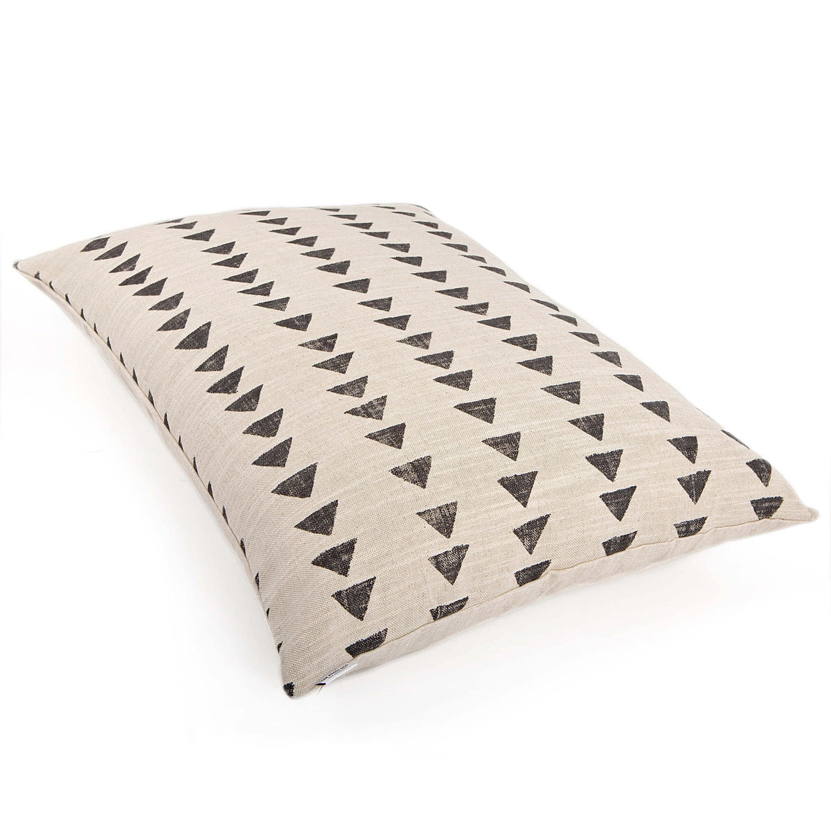 A close-up side view of a medium-sized, beige-colored rectangular dog bed from THE FOGGY DOG, featuring black geometric shapes, including triangles, on its surface. Made in the USA from durable cotton fabric, this plump dog bed showcases a woven texture. The background is white.
