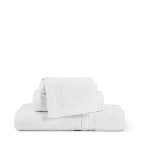A neatly folded set of the Frette North America FEARRINGTON LIFESTYLE TOWEL COLLECTION - WASH CLOTH, made from 100% plush cotton, is stacked against a white background. These wash cloths, inspired by the elegance of Fearrington House Inn, feature a subtle decorative band pattern and vary in size. The overall aesthetic is clean, simple, and minimalist.