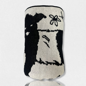 Presenting the FEARRINGTON SIGNATURE COLLECTION - BELTIE BARNYARD KNIT THROW by CALHOUN & CO., this cylindrical knitted item showcases a black and white design with a close-up of a rabbit holding a flower. Made in America, it features minimal detailing that emphasizes contrasting shades, creating a simple and stylized depiction of the rabbit and flower.