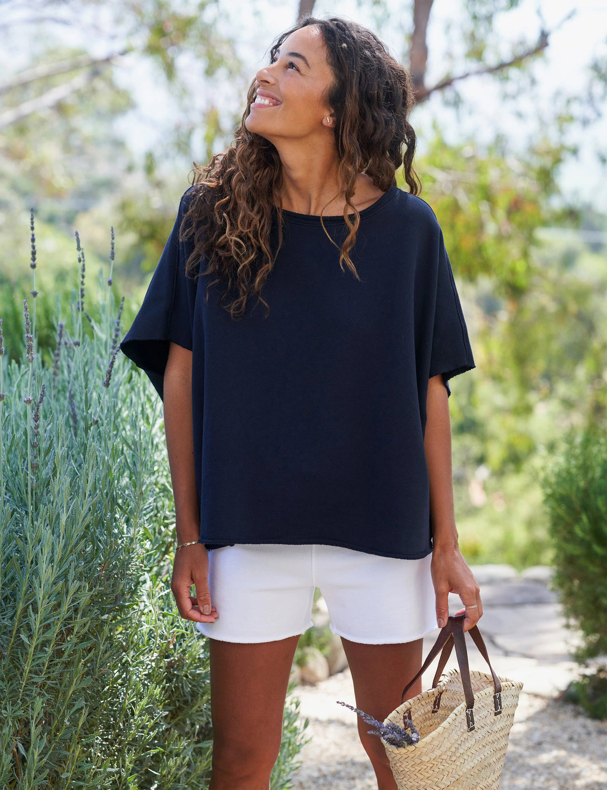 The FRANK &amp; EILEEN OLIVE ORIGINAL CAPELET in black, by FRANK &amp; EILEEN, is a black oversized T-shirt with a round neckline and short, wide sleeves. Made from 100% cotton, it features a loose fit and simple design reminiscent of a capelet against a light textured background.