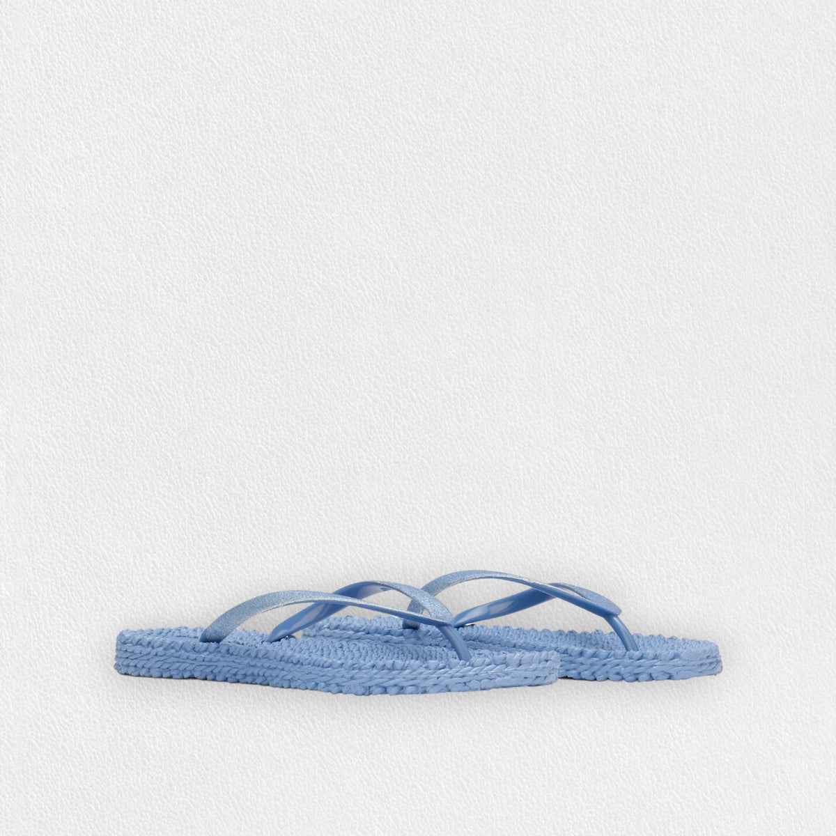 Introducing the ILSE JACOBSEN - CHEERFUL SLIPPER IN LIGHT REGATTA by LINES OF DENMARK, a pair of light blue flip-flops featuring woven straw soles and simple straps. These lightweight flip-flops, showcased against a plain white background, exude a minimalistic and casual style while ensuring a comfortable fit.