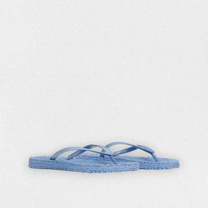 Introducing the ILSE JACOBSEN - CHEERFUL SLIPPER IN LIGHT REGATTA by LINES OF DENMARK, a pair of light blue flip-flops featuring woven straw soles and simple straps. These lightweight flip-flops, showcased against a plain white background, exude a minimalistic and casual style while ensuring a comfortable fit.