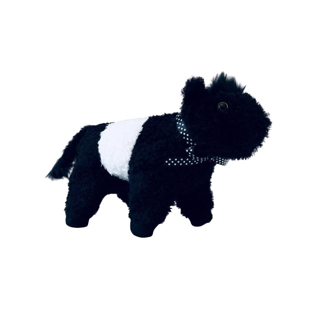 A soft plush toy from the Beverly Hills Teddy Bear Co&#39;s Fearrington Signature Collection, resembling a black and white Belted Galloway cow, stands against a plain white background. This furry mascot features black fuzzy fur on its head, legs, and tail, with a white fuzzy band around its midsection, characteristic of the Galloway breed.