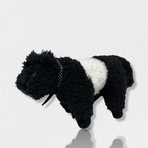 A soft plush toy from the Beverly Hills Teddy Bear Co's Fearrington Signature Collection, resembling a black and white Belted Galloway cow, stands against a plain white background. This furry mascot features black fuzzy fur on its head, legs, and tail, with a white fuzzy band around its midsection, characteristic of the Galloway breed.