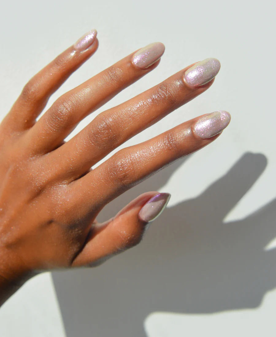 A glass bottle of TENOVERTEN - NAIL POLISH from the brand TEN OVER TEN, featuring a white cap and a dusty pink nail color. The front label displays "TEN OVER TEN" in white uppercase letters. This vegan, eight-free formula ensures both beauty and peace of mind. The background is plain and light-colored.