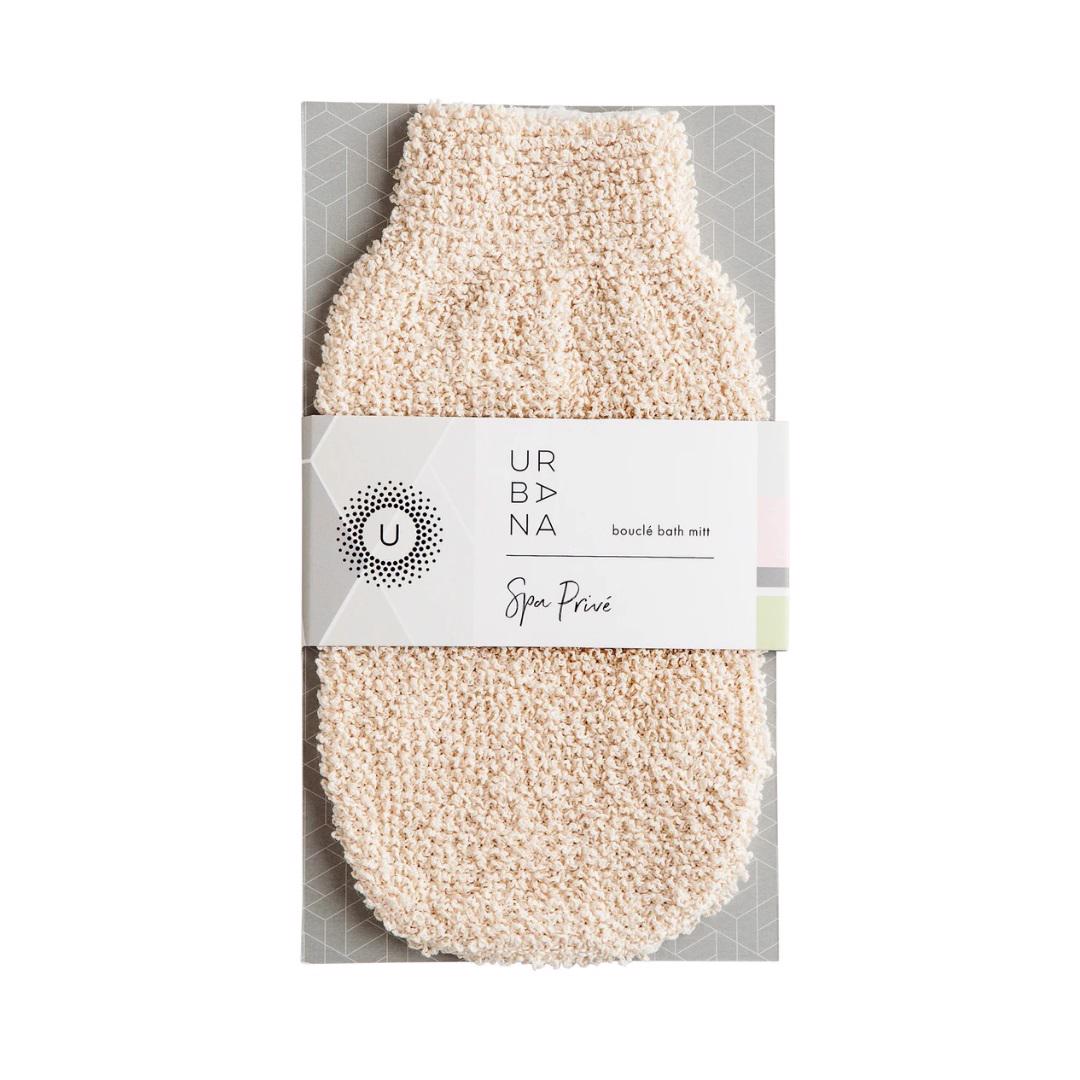 The image depicts a packaged BOUCLE BATH MITT from EUROPEAN SOAPS, LLC. The mitt, crafted from textured beige material, is perfect for exfoliation and cleansing. The packaging showcases geometric patterns and prominently displays the product name in black and white text.