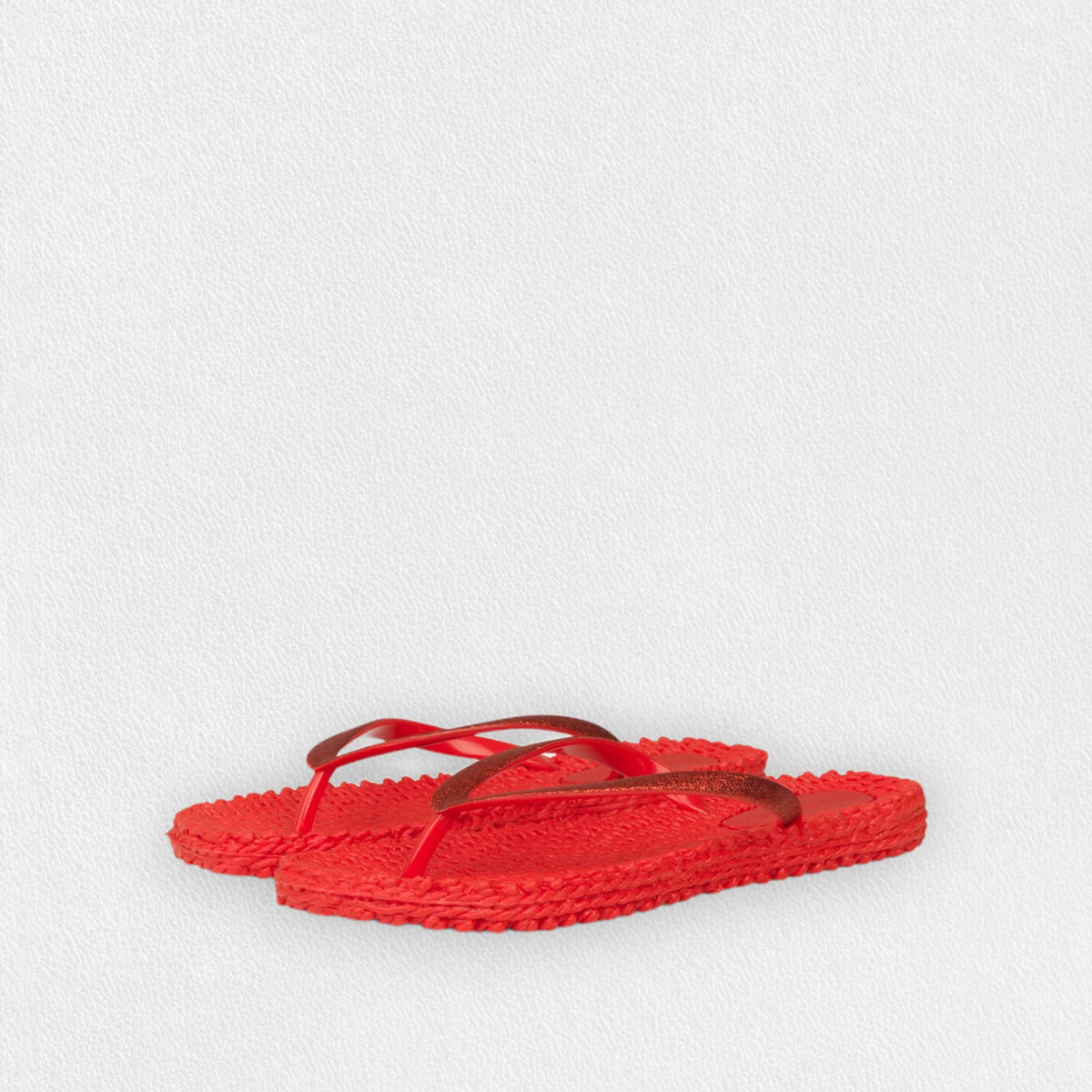 The ILSE JACOBSEN CHEERFUL FLIP FLOP IN DEEP RED by LINES OF DENMARK features vibrant red sandals with textured soles, glitter straps, and a comfortable fit, elegantly placed on a plain white surface.