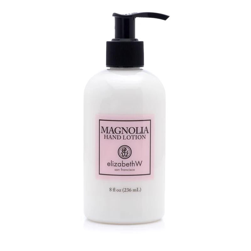 A white plastic bottle of MAGNOLIA HAND LOTION by E WIGHTMAN &amp; CO is depicted against a white background. The bottle includes a black pump dispenser and features a pink label with black text, highlighting its hydrating properties. Enriched with shea butter and vitamin E, this 8 fl oz (236 mL) lotion is designed to keep your skin moisturized.
