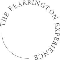 A circular loading icon composed of several gray rectangular segments arranged to form a ring. The segments, which are uniform in shape and size, are darker on their top edges, creating a gradual gradient effect towards the bottom. The center of the circle is transparent. Fearrington Village