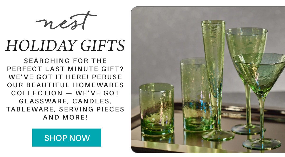 Advertisement for Nest holiday gifts featuring green glassware, including glasses and vases, on a tray. Text invites customers to shop for homeware, tableware, candles, and more. "Shop Now" button included. Fearrington Village