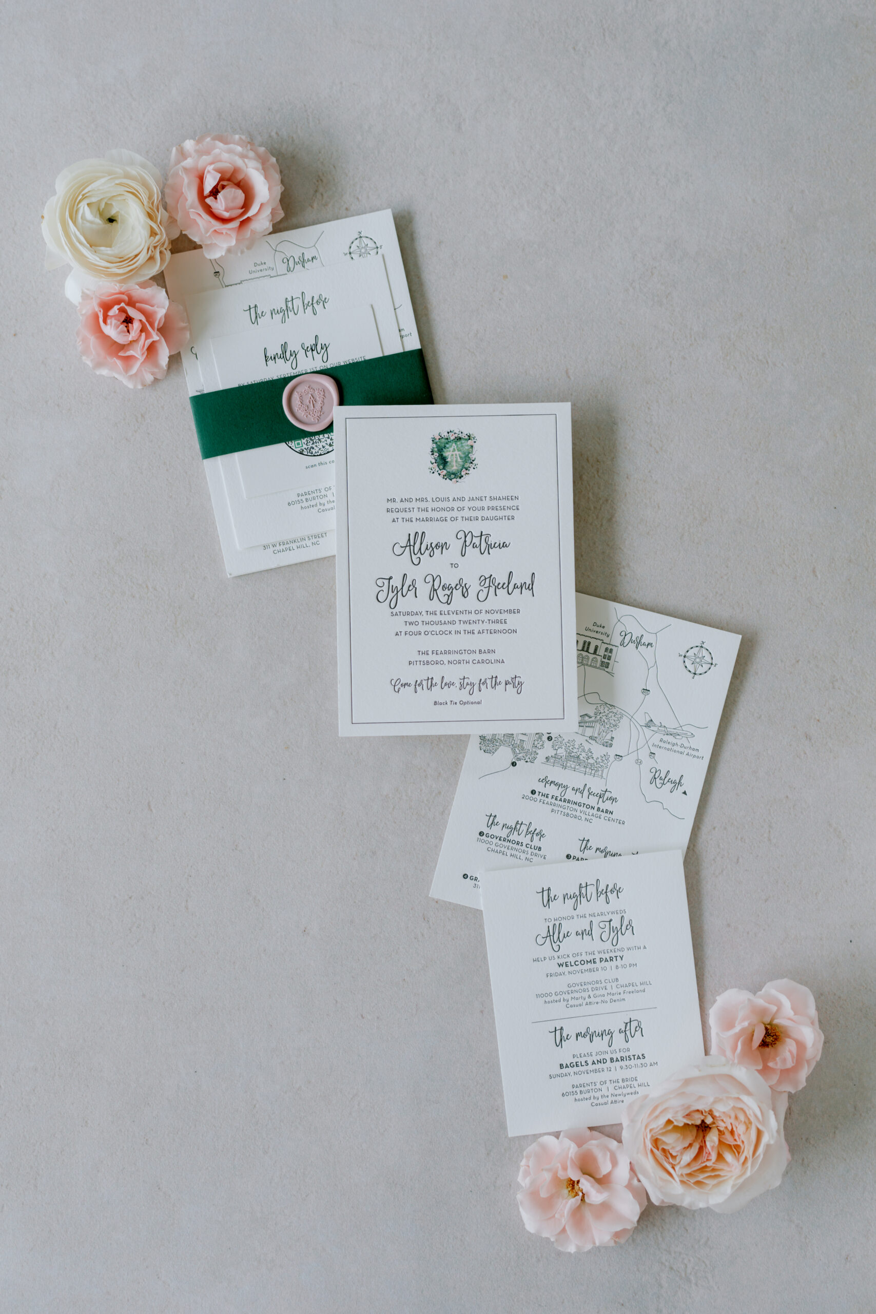 Flat lay of elegant wedding invitations and RSVP cards, surrounded by pink and white roses on a light grey surface. The invitations feature delicate calligraphy and a green ribbon with a wax seal, providing a sophisticated and romantic touch. Fearrington Village