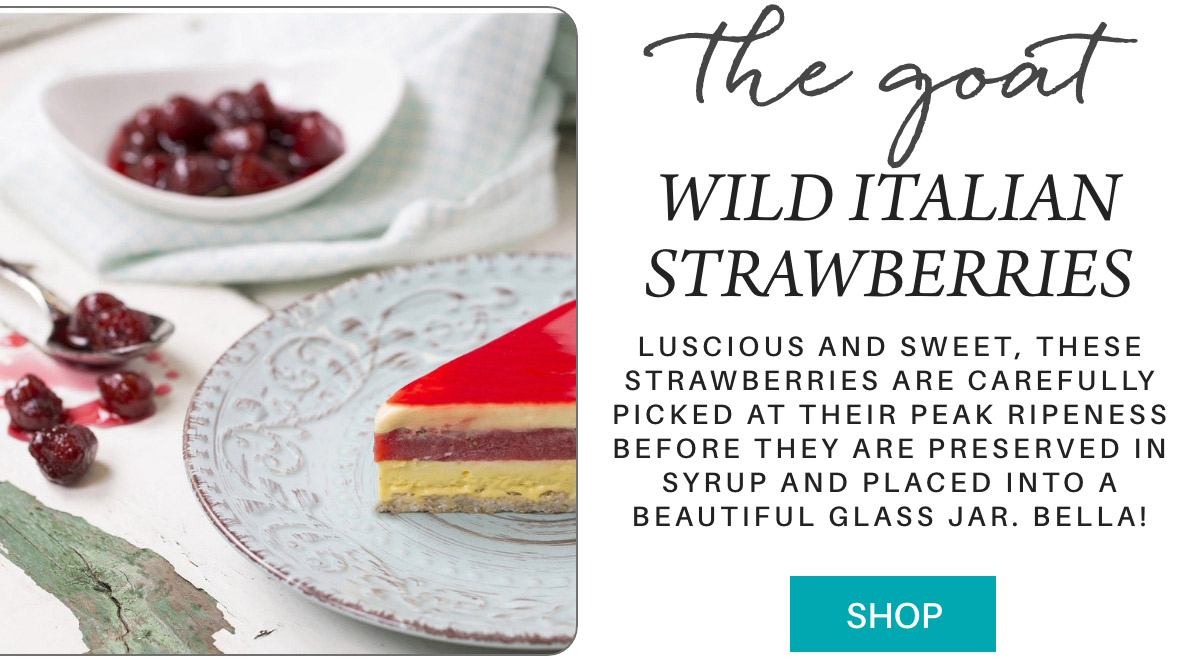 A slice of layered dessert with red, yellow, and white layers on a decorative plate sits on a table next to a small bowl of cherries. Text reads, "the goat WILD ITALIAN STRAWBERRIES" and describes the strawberries as luscious, sweet, and preserved in syrup. A "SHOP" button is at the bottom. Fearrington Village