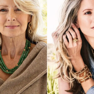 Two women are pictured wearing jewelry. The woman on the left has long blonde hair, wears layered gold bracelets, drop earrings, a green bead necklace, and a beige top. The woman on the right has wavy blonde hair, wears chunky gold rings, bracelets, earrings, and a denim shirt. Both are posing confidently. Fearrington Village