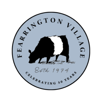 A circular logo with a sketch of a black and white cow in the center. Surrounding text reads "FEARRINGTON VILLAGE" at the top and "CELEBRATING 50 YEARS" at the bottom. The middle text reads "Est'd 1974" in a handwritten font. The background is light blue. Fearrington Village