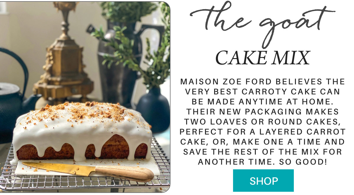 An advertisement for "The Goat Cake Mix" by Maison Zoe Ford. It features a freshly baked carrot cake with white icing on a cooling rack. The caption highlights the cake mix's quality and new packaging. A button labeled "SHOP" is at the bottom right. Fearrington Village