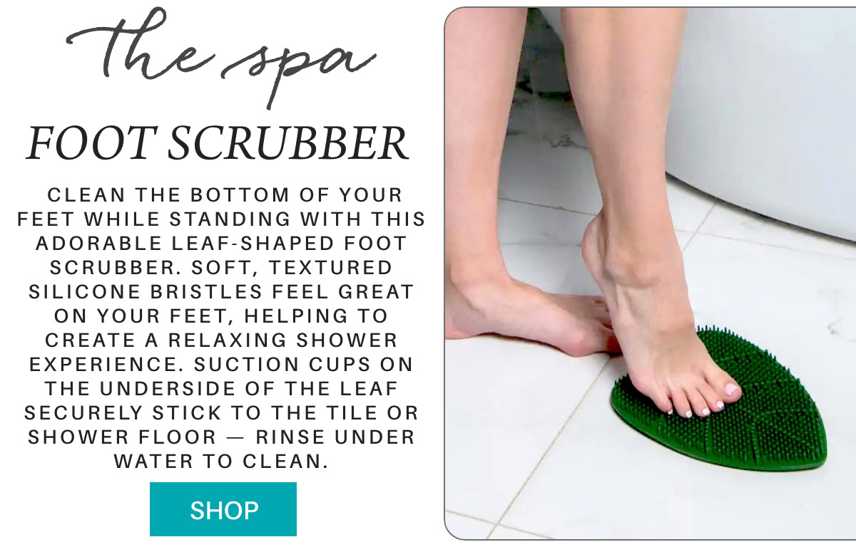 Image of a person using a leaf-shaped foot scrubber in a bathroom. The foot scrubber has soft, textured silicone bristles and is securely affixed to the floor with suction cups. Text on the left describes the scrubber and a "Shop" button is displayed at the bottom. Fearrington Village