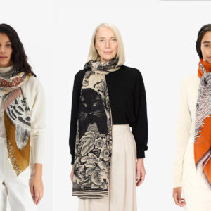 Inoui Editions. Three women are shown wearing stylish scarves. The woman on the left wears a white sweater with a multi-colored scarf. The woman in the center sports a black top with a patterned scarf. The woman on the right has a cream top with an orange scarf. Fearrington Village