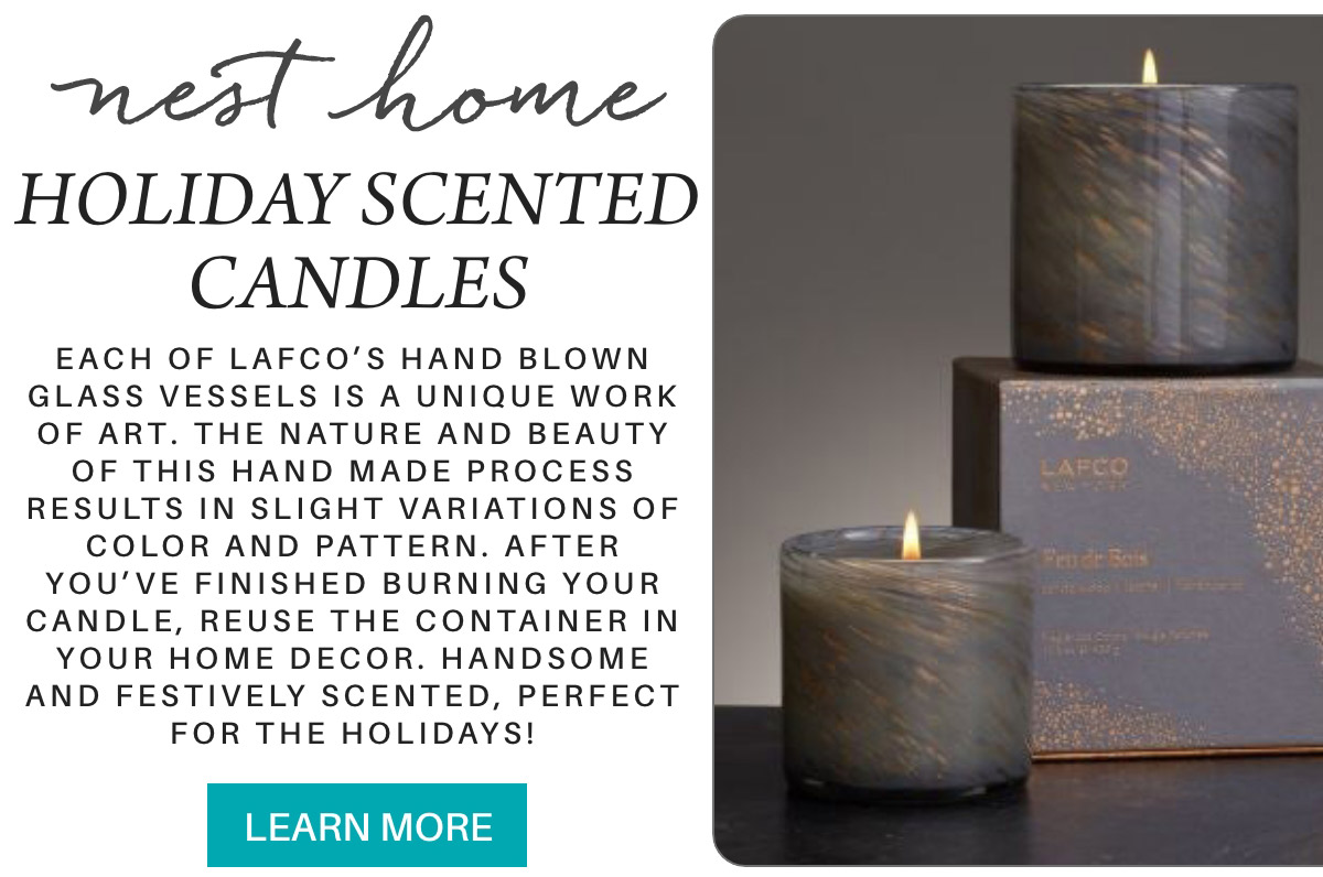 An advertisement for Nest Home holiday scented candles by LAFCO. The image shows two candles in artistic glass vessels, one lit and one with packaging. Text highlights the handmade nature, unique patterns, and use as home decor. Includes a "Learn More" button. Fearrington Village