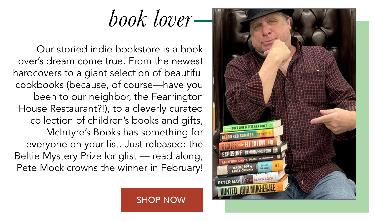 A man in a hat sits in a chair, holding several colorful books. Text describes McIntyre's Books as a dream come true for book lovers, offering a variety of genres. It mentions new releases and a mystery prize. A "Shop Now" button is included. Fearrington Village