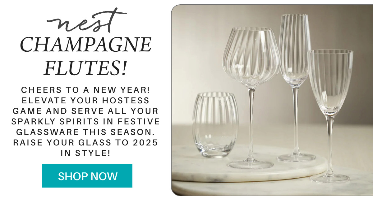 A promotional image for Nest champagne flutes featuring four elegantly shaped glasses on a marble surface. The text advertises festive glassware for the New Year and encourages shopping for 2025 celebrations. Fearrington Village