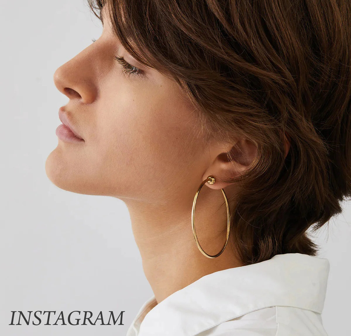 Person with short brown hair wearing large gold hoop earrings and a white collared shirt, looking to the side against a neutral background. The word "INSTAGRAM" is in the lower left corner. Fearrington Village