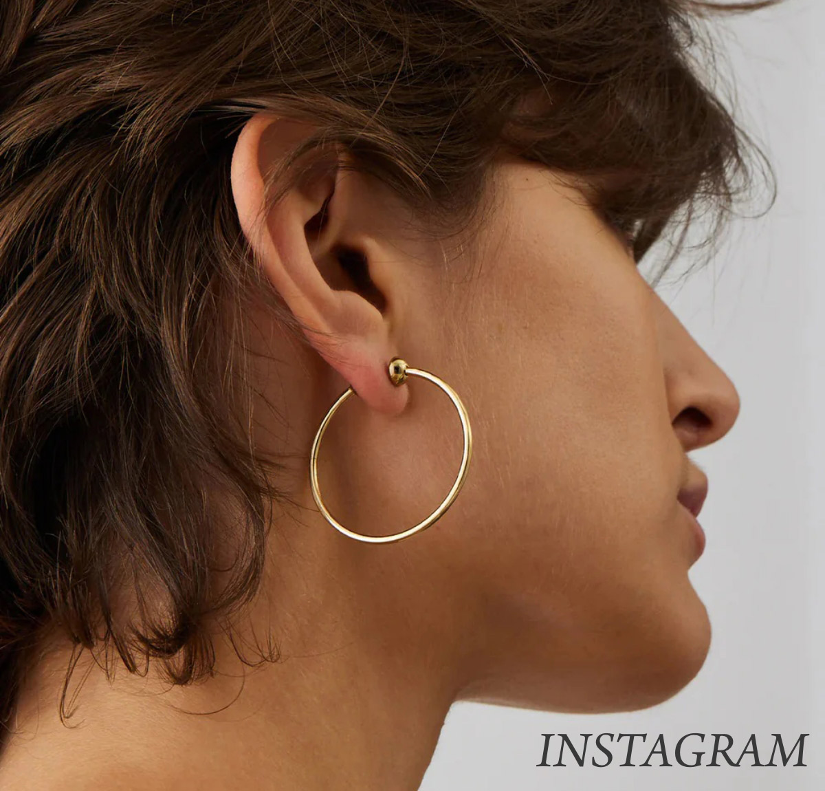 Person with short brown hair wearing a large gold hoop earring on their left ear. They are facing away from the camera against a plain background. The word "INSTAGRAM" is in the bottom right corner. Fearrington Village