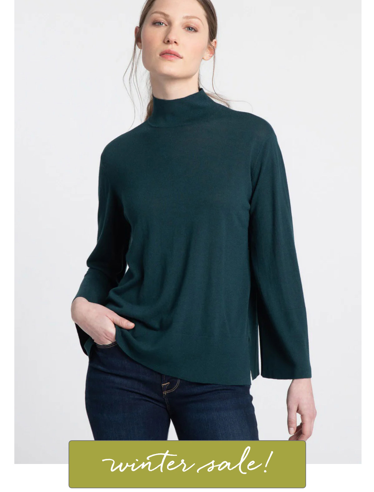 A person stands wearing a dark green turtleneck and dark jeans. They have one hand in their pocket. Text at the bottom says "winter sale!" in cursive on a green background. Fearrington Village