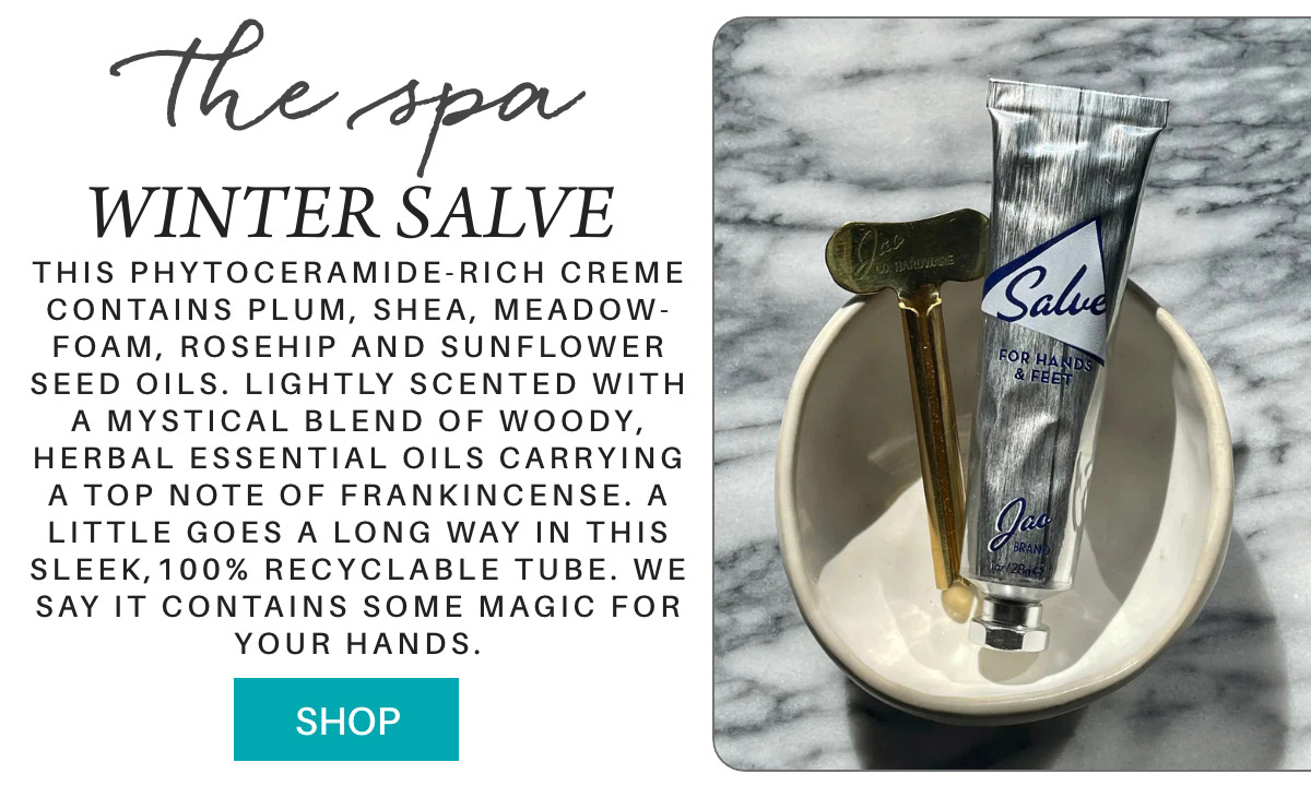 A silver tube of winter salve rests on a small dish, accompanied by a golden key. The text describes the salve as phytoceramide-rich and scented with essential oils, offering moisturizing benefits for hands and feet. A "Shop" button is at the bottom. Fearrington Village