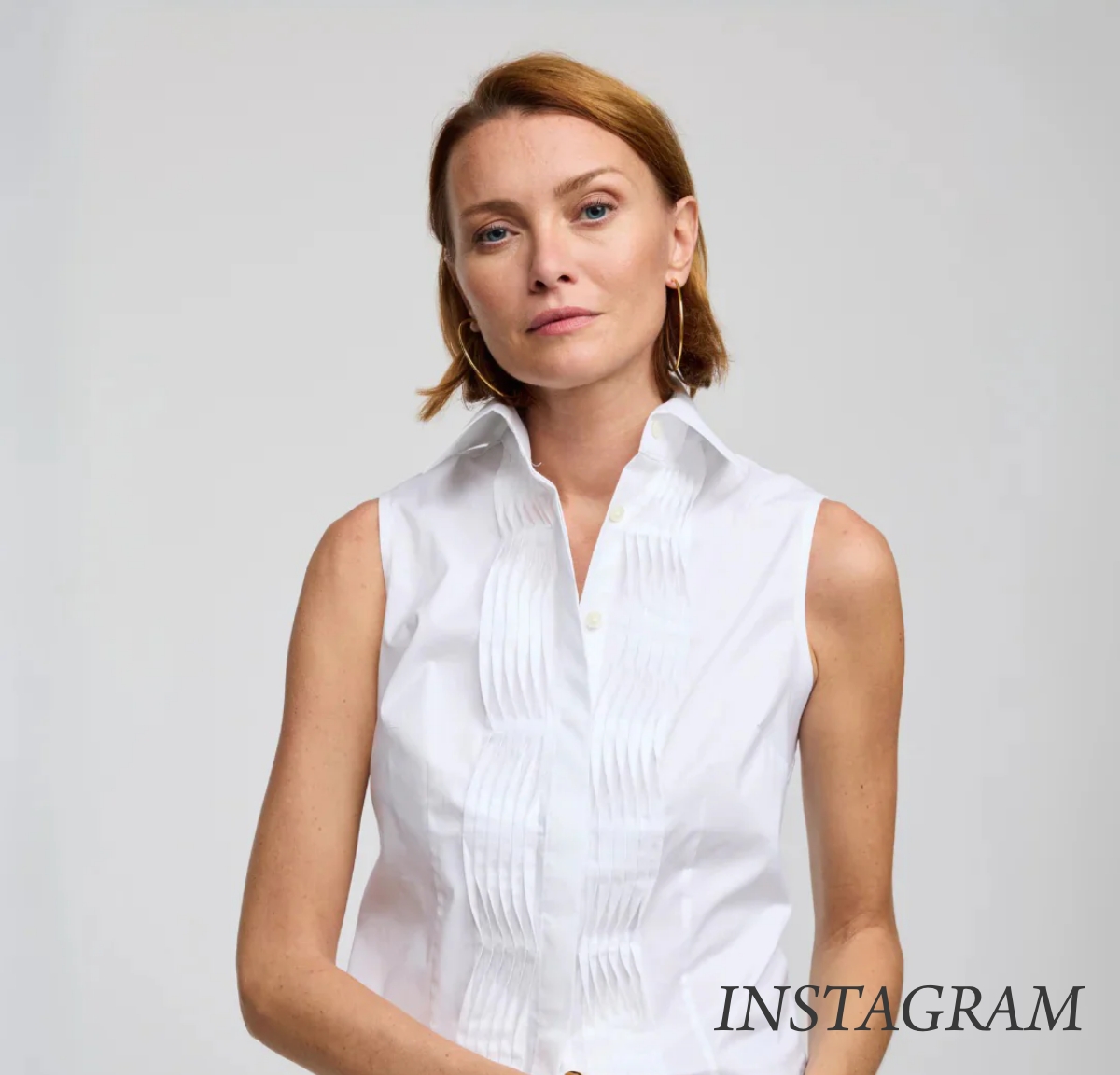 Woman with short red hair wearing a sleeveless white blouse. She stands against a plain background, looking at the camera with a neutral expression. The word "INSTAGRAM" is in the bottom right corner. Fearrington Village