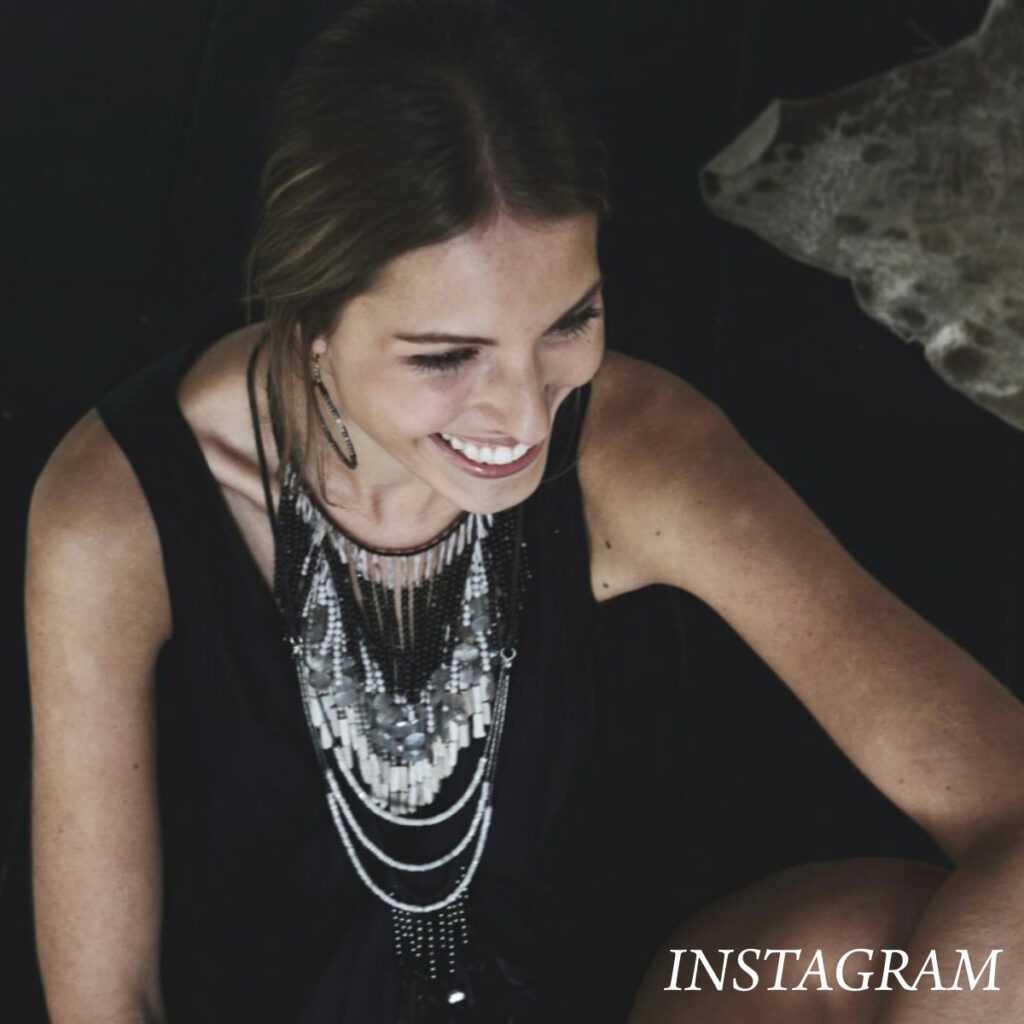 Smiling woman with long hair looks to the side, wearing a layered necklace and a black outfit. The word "INSTAGRAM" is in the bottom right corner. Fearrington Village