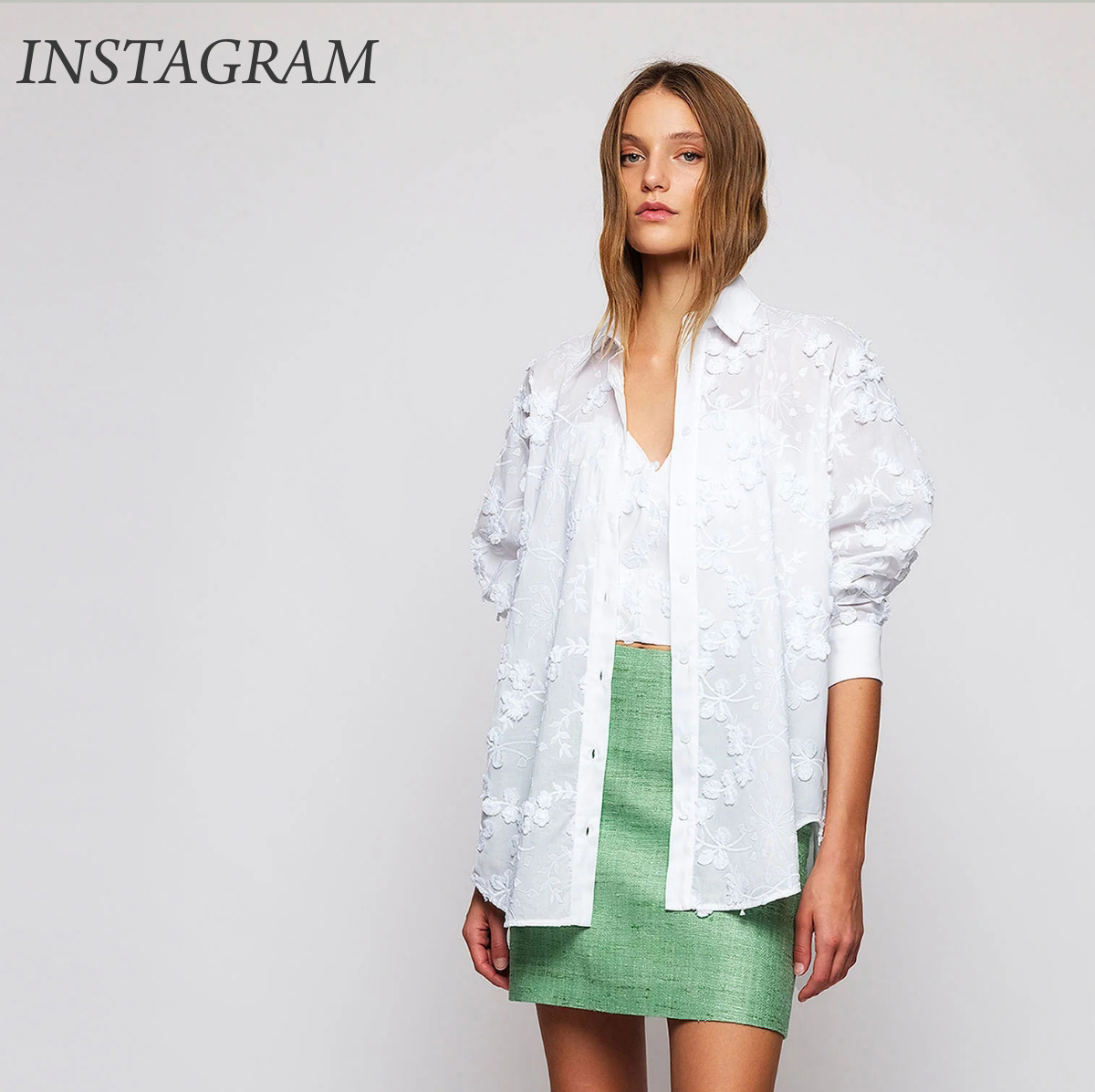 Woman in a loose, white embroidered blouse over a white top and a short green skirt, standing against a plain background. "INSTAGRAM" is written in the top left corner. Fearrington Village