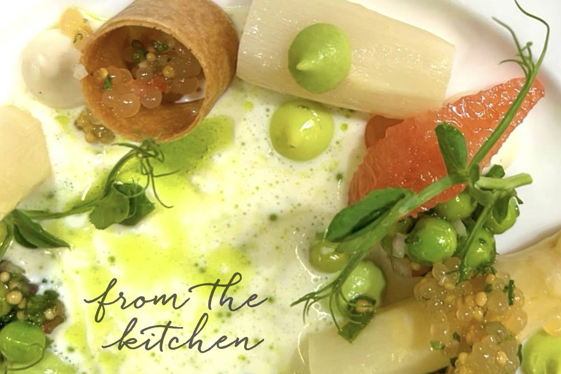 A gourmet dish features white asparagus, green peas, grapefruit, microgreens, and a crisp pastry with roe, artfully plated with green sauce; the words “from the kitchen” appear in cursive text. Fearrington Village