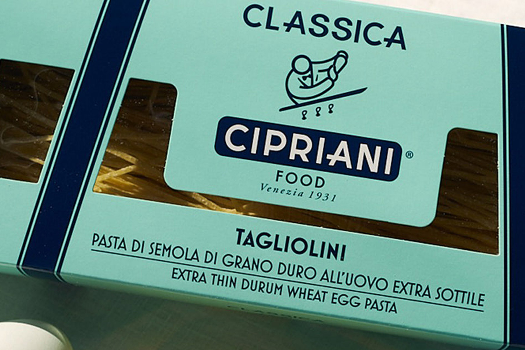 Mint green packaging of Cipriani Tagliolini pasta from Venezia, 1931. The box says "Classica" and features a logo with a chef. Label reads "Pasta di semola di grano duro all’uovo extra sottile" and "Extra thin durum wheat egg pasta. Fearrington Village