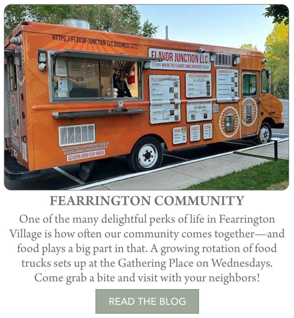 An orange food truck with a serving window is parked outdoors with menu boards displayed. Trees and grass are visible in the background, and the truck advertises Flavor Junction LLC. "One of the many delightful perks of life in Fearrington Village is how often our community comes together—and food plays a big part in that. A growing rotation of food trucks sets up at the Gathering Place on Wednesdays. Come grab a bite and visit with your neighbors!" Fearrington Village