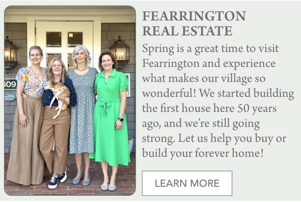 Four women stand smiling on a brick porch in front of a house, one holding a small dog. A sign reads “FEARRINGTON REAL ESTATE” with information about the community and a button labeled “LEARN MORE.”. "Spring is a great time to visit Fearrington and experience what makes our village so wonderful! We started building the first house here 50 years ago, and we’re still going strong. Let us help you buy or build your forever home!" Fearrington Village