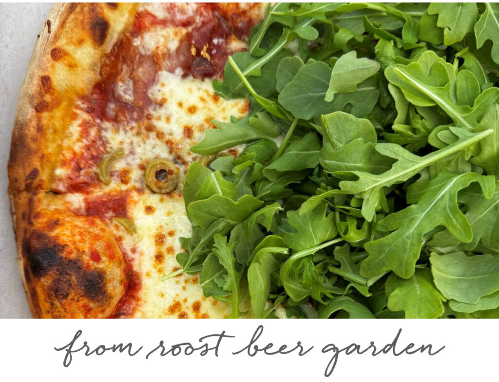 The Fearrington Plate - May 1, 2025 5 Half of a pizza topped with melted cheese, olives, and tomato sauce is covered with fresh arugula leaves. Below the image, handwritten text reads "from roost beer garden. Fearrington Village